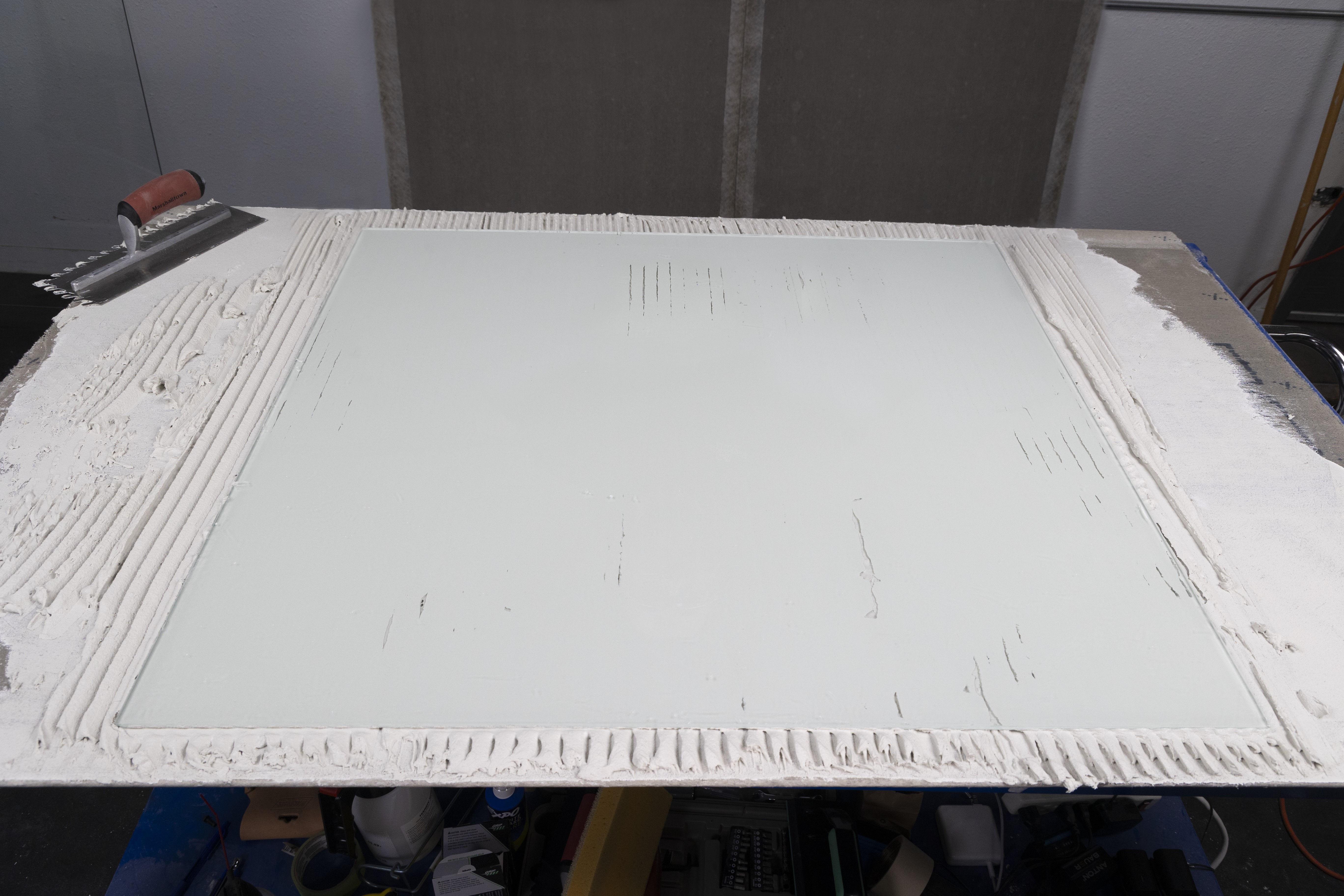 a large glass tile shows the coverage rates of the LayFlat Notched trowel